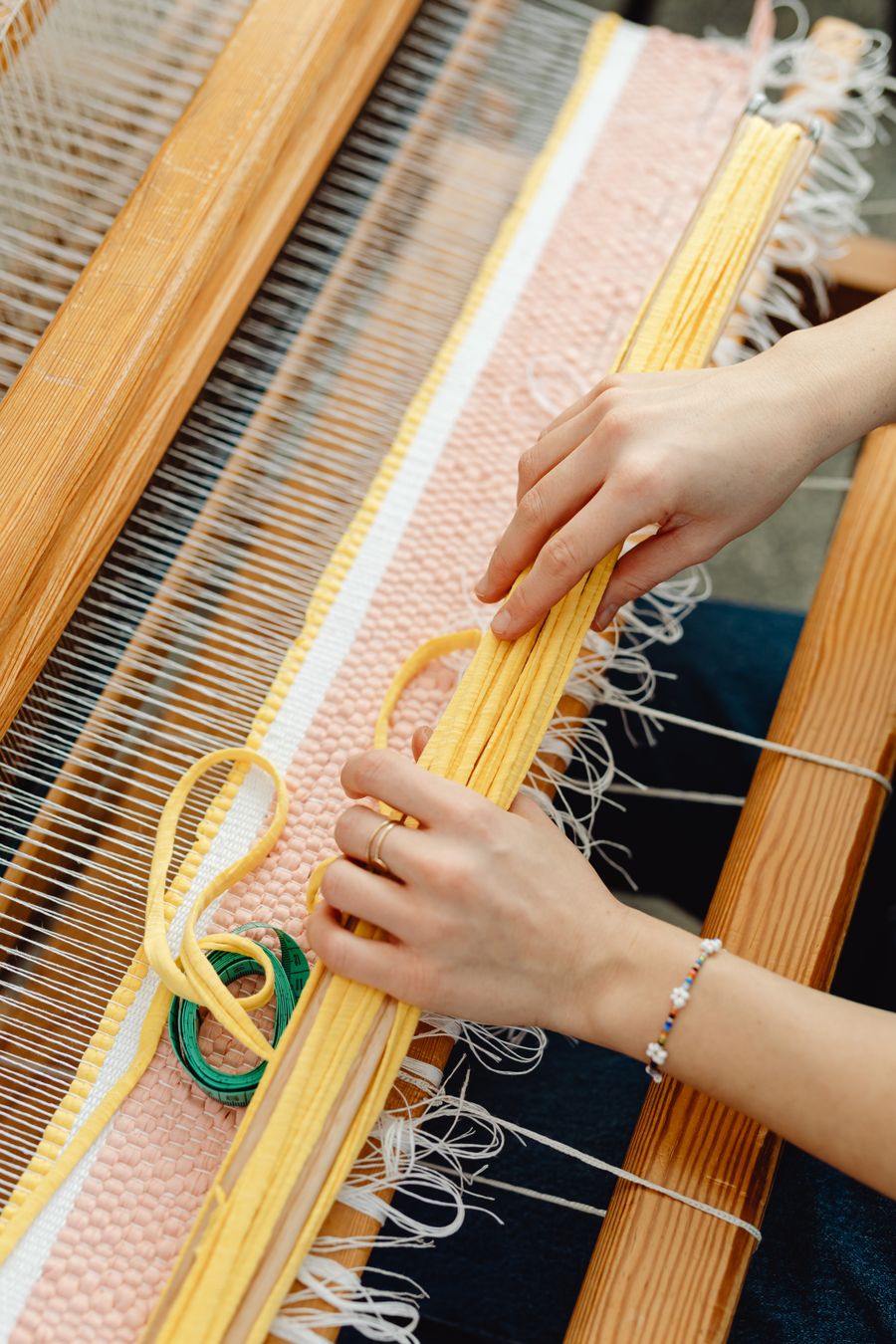 Hands weaving on a wooden loom